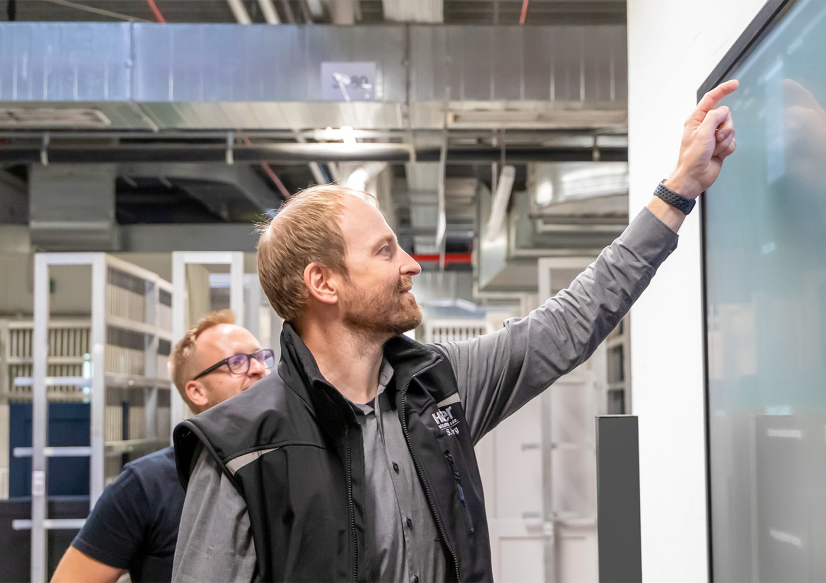 Image of employees in the production department at Häcker Küchen looking together at a screen